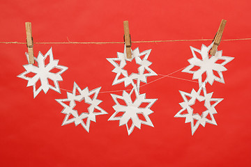 Image showing snowflakes produced by child hanging on red background