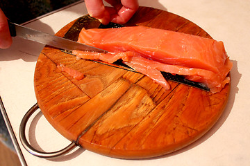 Image showing  hand cuts slices of red fish