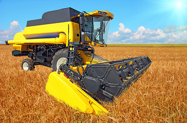 Image showing combine harvester on a wheat field with a blue sky