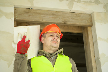 Image showing Builder with a concrete block on shoulder at new building