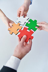 Image showing Group of business people assembling jigsaw puzzle