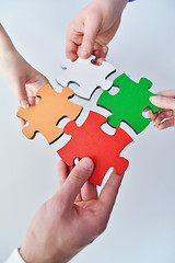 Image showing Group of business people assembling jigsaw puzzle