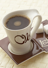 Image showing choco latte. A white cup of coffee on a support.