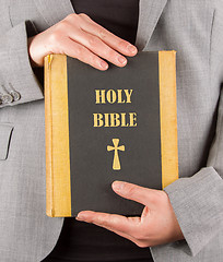 Image showing Woman in business suit is holding a holy bible