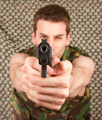 Image showing Soldier in camouflage vest is holding a gun