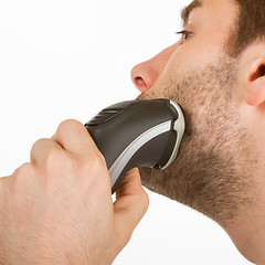Image showing Young man shaving his beard off