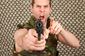 Image showing Soldier in camouflage vest is holding a gun