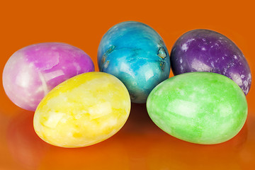Image showing Easter eggs in different colors on an orange background
