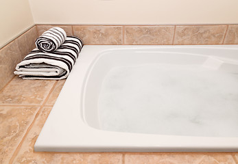Image showing Folded striped towels and bath with foam