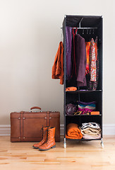 Image showing Mobile wardrobe with clothing and leather suitcase