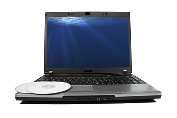 Image showing White cd`s on a laptop isolated. Nice rays of light on desktop.