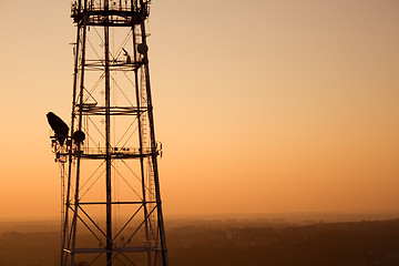 Image showing Communication tower at sunset with cityscape