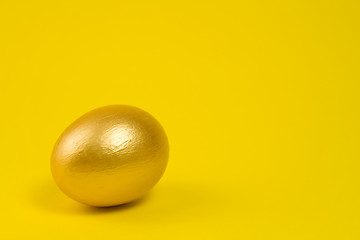 Image showing Golden egg on yellow background. Lots of space for text