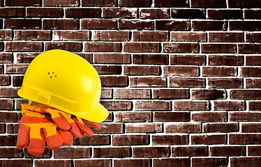 Image showing Yellow hard hat and protective gloves with grunge wall backgroun