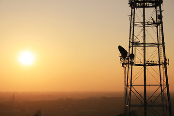 Image showing Communication tower at sunset with cityscape