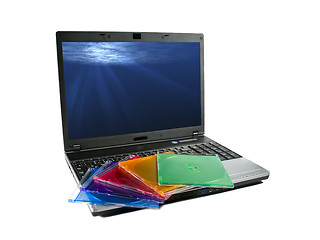 Image showing Colored cd`s on a laptop isolated. Nice rays of light on desktop