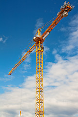 Image showing Tall white tower crane against bright blue sky.