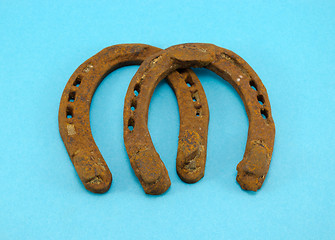 Image showing retro rusty pair of horseshoes on blue background 