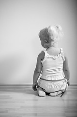 Image showing  little girl sits on her knees facing the wall 