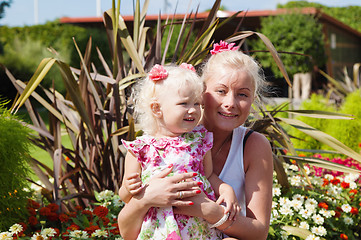 Image showing Mum with a small daughter among flowers  in park