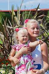 Image showing Mum with a small daughter among flowers  in park