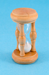 Image showing wooden sand glass clock stand on blue background 