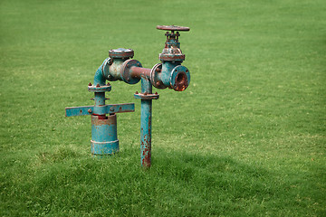 Image showing Water pipe on green grass meadow