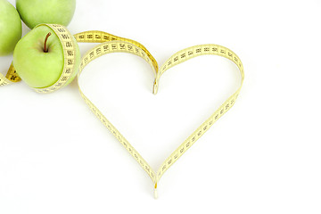 Image showing green apple with a measuring tape and heart symbol isolated