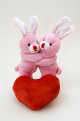 Image showing Two bunny hug each other close to the plush heart 