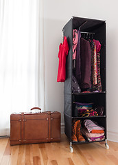 Image showing Leather suitcase and mobile wardrobe with clothing