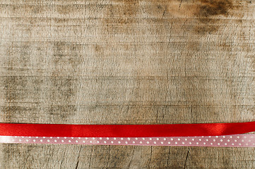 Image showing Red ribbon for gift wrap on wooden background