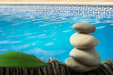 Image showing Stacked stones on wooden base for spa and green leaf