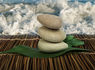 Image showing Stacked stones on wooden base for spa and green leafs