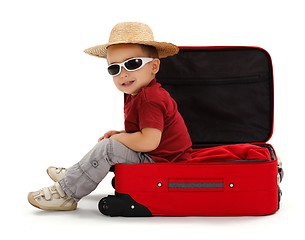 Image showing Confident little boy wearing straw hat, sitting in suitcase