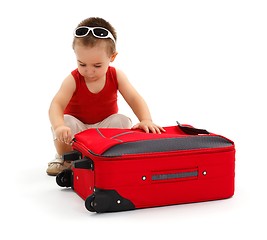 Image showing Little boy preparing for trip, zipping suitcase