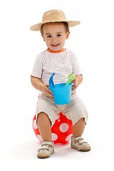 Image showing Little boy sitting on dotted ball, holding sandbox toys