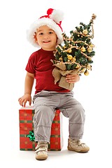 Image showing Little christmas boy sitting on present, holding Christmas tree