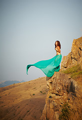 Image showing A girl stands on the edge of a cliff.