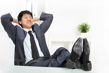Image showing Asian businessman relaxing with his feet up