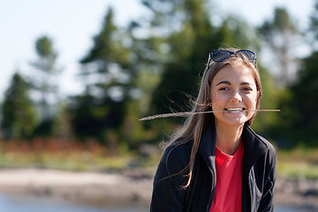 Image showing beautiful girl with an ear in his teeth against the backdrop of 