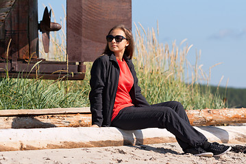 Image showing Girl on a deserted beach in the background of an old rusty screw