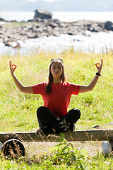 Image showing girl in a red dress sitting on a bench in the lotus position