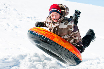Image showing Boy up in the air on a tube in the snow