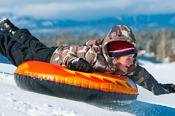 Image showing Happy boy riding a tube in snow