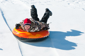 Image showing Happy boy sleding on a tube.