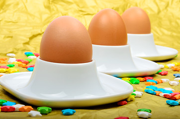 Image showing Colorful stars three eggs and egg cups are golden background