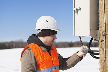 Image showing Electrician with electrical cable in the hands near switchboard