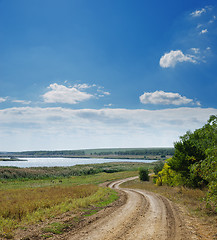 Image showing rural road near river under cloudy sky