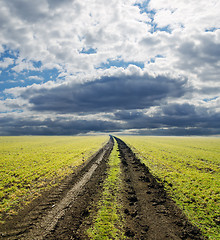 Image showing rural road in green field under dramatic sky