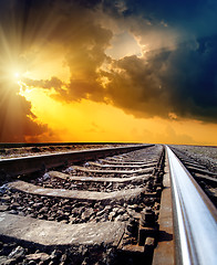 Image showing railway to horizon under dramatic sky with sun